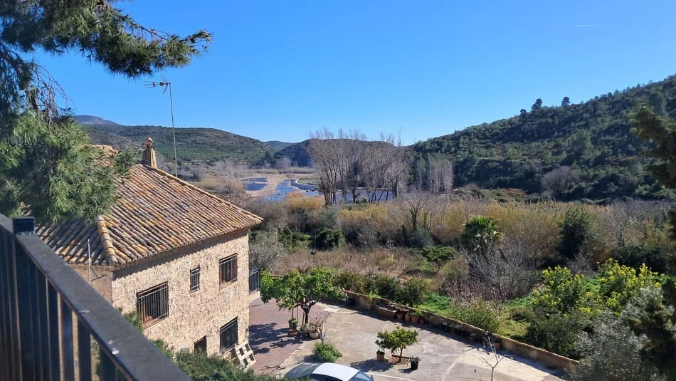Paisaje de campo donde se ve riachuelo y casa