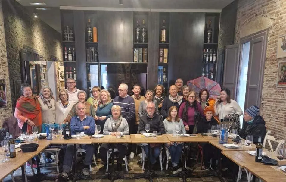 Grupo de personas detrás de una mesa en forma de L y con una estantería de fondo