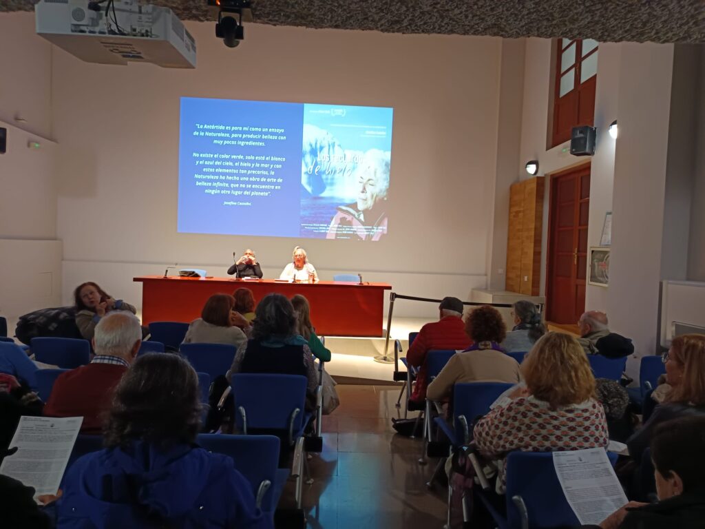 Sala con una proyección en pantalla y público sentado en sillas azules
