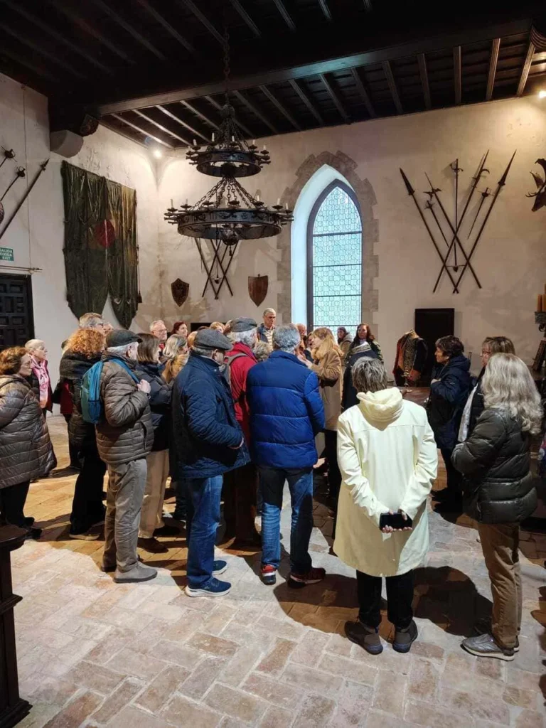 Grupo de personas en una sala con armas de época en la pared