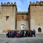 Grupo de personas posando delante de la entrada de un edificio antiguo con dos torres