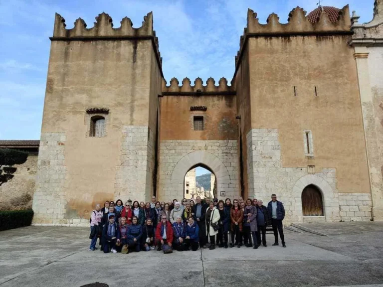 Grupo de personas posando delante de la entrada de un edificio antiguo con dos torres