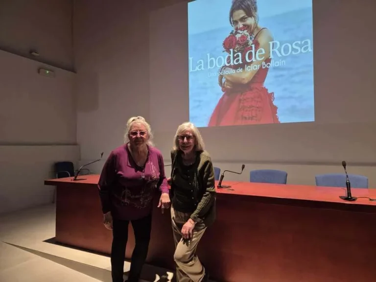 Dos mujeres posando delante de una mesa de conferencia