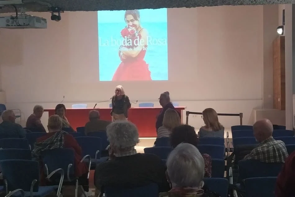 Sala con público sentado frente a proyección de una imagen de mujer