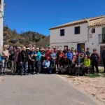 Grupo de personas posando en grupo en la calle de un pueblo con casas blancas de fondo