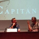 Un hombre y una mujer hablando en una sala de ponencias