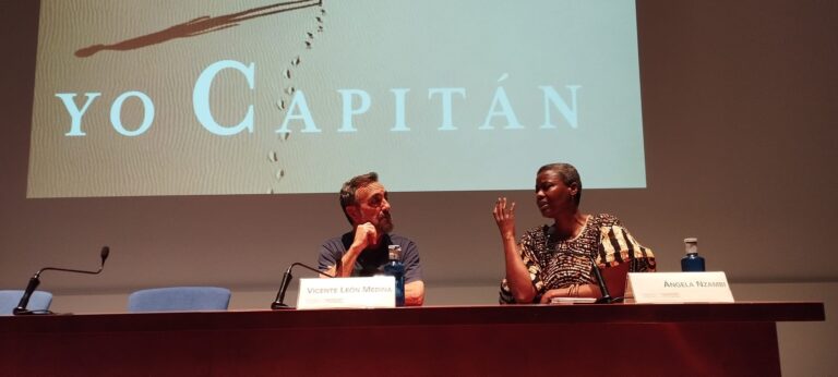 Un hombre y una mujer hablando en una sala de ponencias