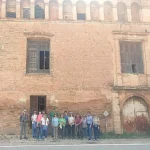 Grupo de personas delante de un edificio antiguo con arcos en la parte superior