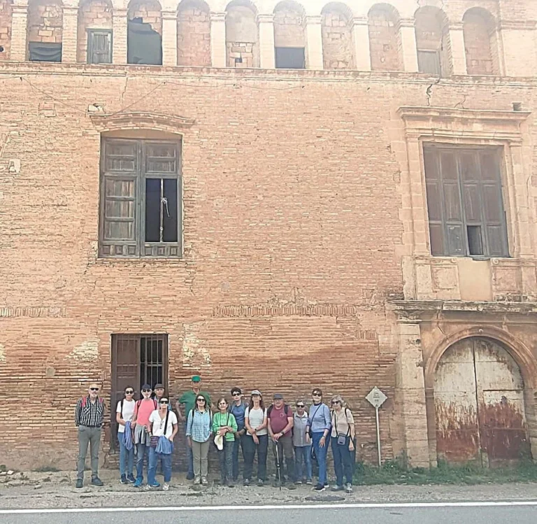 Grupo de personas delante de un edificio antiguo con arcos en la parte superior