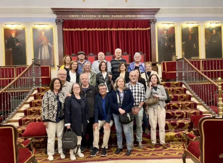 Grupo de personas mayores posando en unas escaleras enmoquetadas sojas