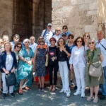 Grupo de personas mayores posando delante de un edificio antiguo