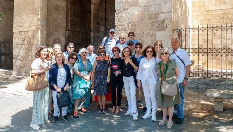 Grupo de personas mayores posando delante de un edificio antiguo