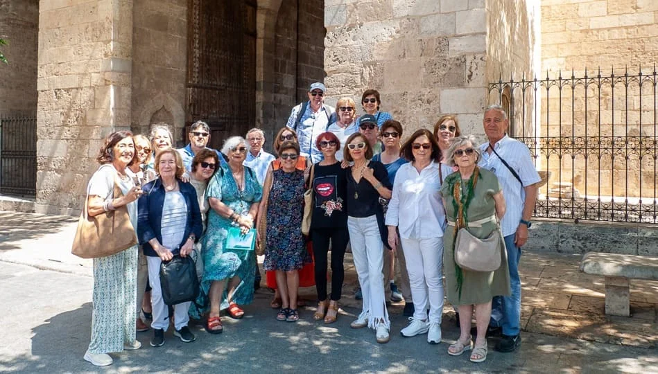 Grupo de personas mayores posando delante de un edificio antiguo
