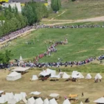 Campo con tropas, tiendas de campaña y público