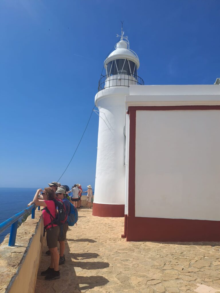 Faro blanco en cielo azul y personas mirando