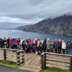 Grupo de personas ante lago y montañas